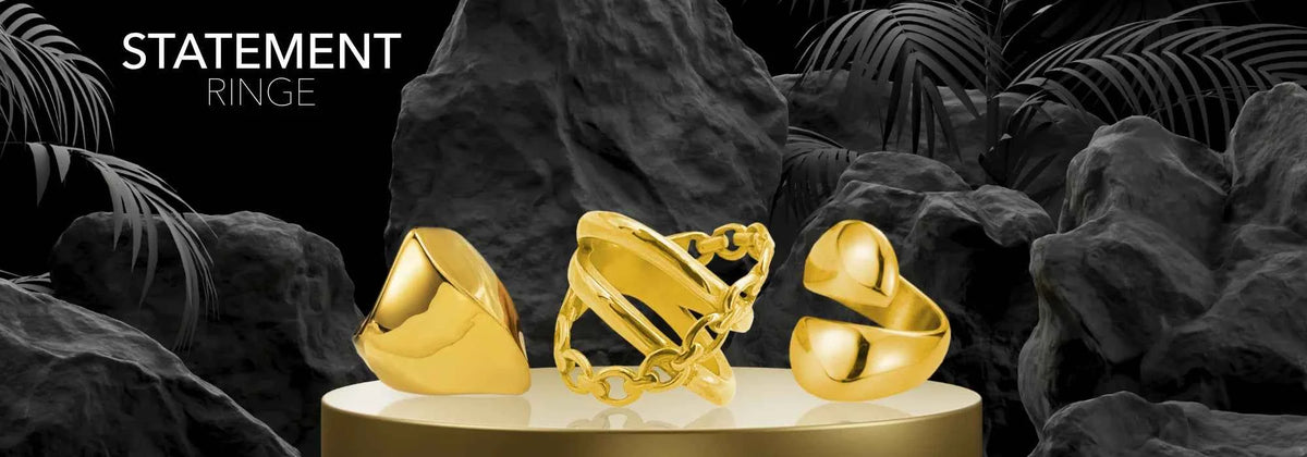 Goldene Statement Ringe auf dunklem Podest – Statement Ringe Kollektion bei Sucre Fine Jewelry